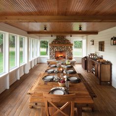 a long wooden table with plates and silverware on it in front of a fireplace