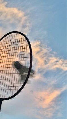 a tennis racket with the sky and clouds in the backround, as seen from below