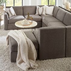 a living room filled with lots of furniture and pillows on top of a white rug