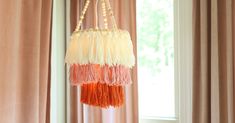 an orange, white and pink hanging decoration in front of a window with drapes