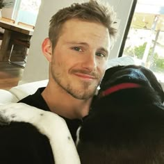 a man is sitting on a couch with his black and white dog in front of him