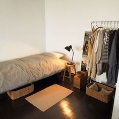 a bedroom with a bed, clothes rack and other items on the floor in front of it