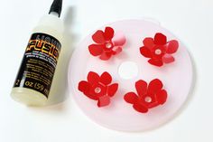 a white plate topped with red flowers next to a bottle of glue