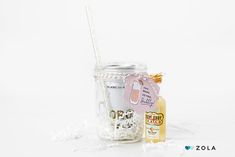 a mason jar filled with white chocolate covered marshmallows next to a bottle of honey