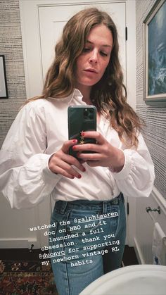 a woman is taking a selfie in the mirror with her cell phone while wearing jeans and a white shirt