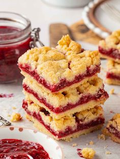 raspberry crumb bars stacked on top of each other with jam in the background