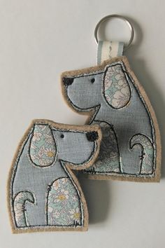 two embroidered keychains with dogs on them, one is blue and the other has white flowers