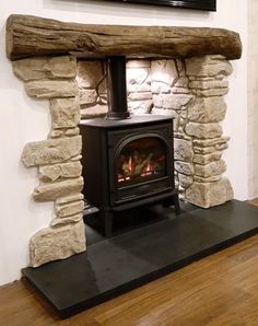 a wood burning stove sitting inside of a living room next to a tv mounted on the wall