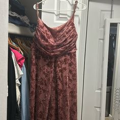 a woman's dress hanging on a rack in front of a closet with clothes