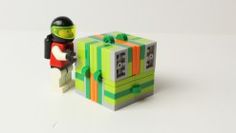 a lego man standing next to a green box