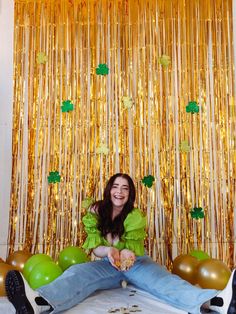 a woman sitting on the floor in front of balloons and streamers with gold foil