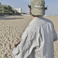 a man standing on top of a sandy beach next to the ocean with buildings in the background