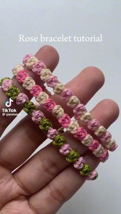 the hand is holding three crocheted bracelets in pink, green and white