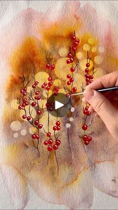 someone is painting some red berries on a piece of paper with watercolor pencils