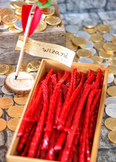 a wooden box filled with red candy canes next to lots of gold and silver coins