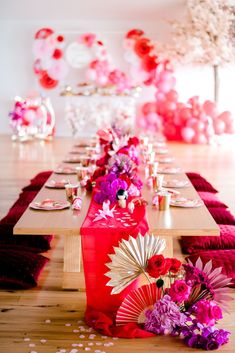 a long table with pink and purple flowers on it is set up for a party