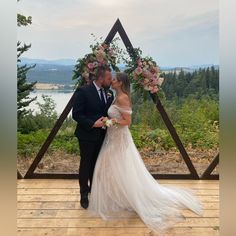 a bride and groom standing in front of a wooden arch with flowers on it at their wedding