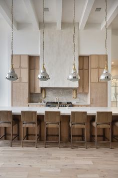 a large kitchen with wooden cabinets and white counter tops, along with two pendant lights hanging from the ceiling