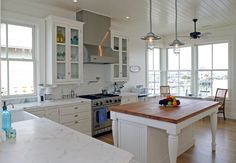 a kitchen with white cabinets and an island in the middle, surrounded by wood flooring