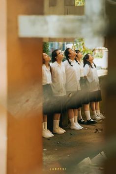 a group of young women standing next to each other in front of a building with their eyes closed