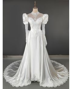 a white wedding dress with long sleeves and lace on the neckline, in front of a mannequin