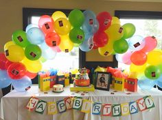 a birthday party with balloons and pictures on the table