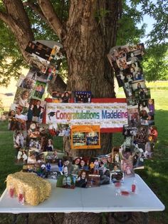 a table topped with pictures under a tree next to a sign that says congratulations maddiene