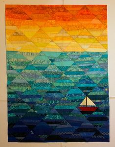 a quilted wall hanging with a sailboat in the ocean