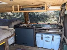 the interior of a small camper with an oven and sink in it, next to two storage containers