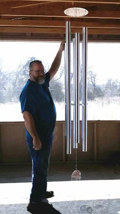 a man standing in front of a wind chime