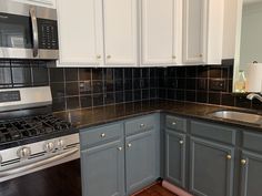 a kitchen with gray cabinets and black counter tops