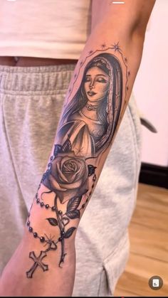 a person with a tattoo on their arm holding a rose and cross in the other hand