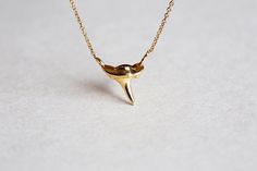 DAINTY GOLD SHARK TOOTH NECKLACE Simple and dainty shark tooth necklace. This piece is the ideal gift for a surfer or an ocean lover.
 DETAILS Pendant   Shape: Shark tooth
   Size: 10 mm  Band   Style: Chain  Material:  14k Gold: yellow, white, rose  18k Gold: yellow, white, rose  Other Metal: platinum   Sizing: We are using US metric system   Customization Options This design can be customized. If you would prefer a custom design, please contact us before purchase. Procedure Information Please Shark Tooth Pendant, Tooth Charm, Silver Necklace Simple, Shark Necklace, Shark Tooth Necklace, Tooth Necklace, Gold Filled Necklace, Solid Gold Necklace, Shark Tooth