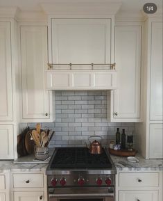 a stove top oven sitting inside of a kitchen next to white cabinets and counter tops