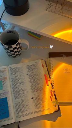 an open book on a table with a cup of coffee and notebooks next to it