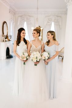 three bridesmaids in white dresses standing next to each other