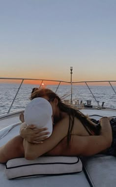 a woman laying on the back of a boat while holding a baby in her arms