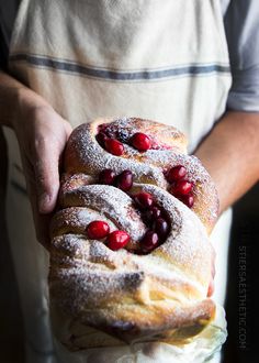 two cranberry rolls are being held by a man in an apron and apron