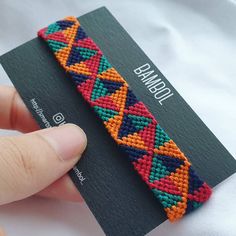 a hand holding a colorful beaded bracelet