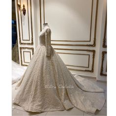 a white wedding dress on display in a room with gold trimmings and an ornate wall