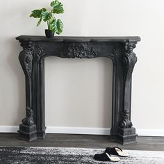 a black fireplace mantel with a potted plant on top