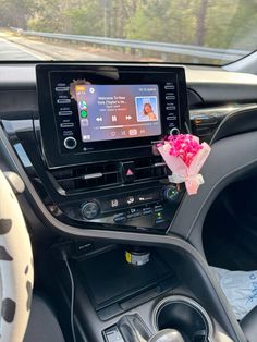 the interior of a car with an entertainment system and steering wheel controls on display, along with pink flowers