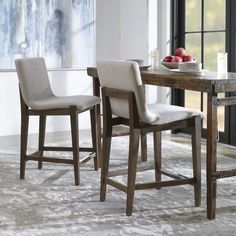 a dining room table with two chairs and a bowl of fruit on top of it