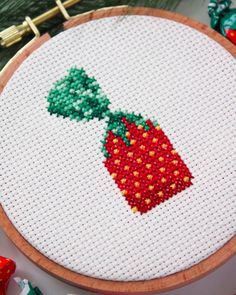 a close up of a cross stitch pattern on a wooden hoop with beads and thread