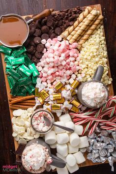 an assortment of candy and marshmallows on a wooden tray