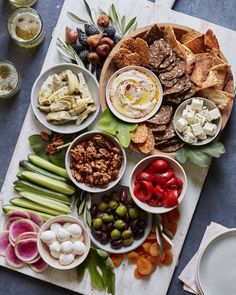 a table topped with bowls filled with different types of food and snacks on top of a cutting board