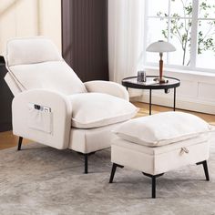 a white reclining chair and ottoman in a living room with a lamp on the side table