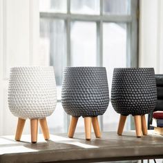 three different colored vases sitting on top of a table next to a bookcase