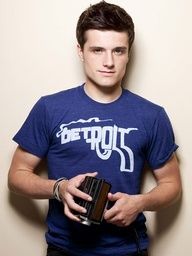 a young man is holding a camera and posing for a photo in front of a wall