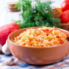 a brown bowl filled with rice next to some vegetables and garlic on a checkered table cloth